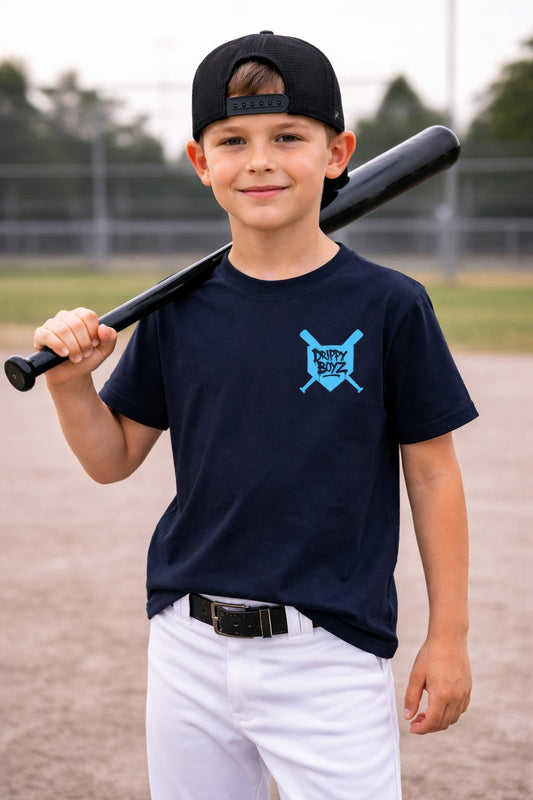 Young boy holding a baseball bat on a baseball field wearing a navy blue t-shirt with a logo.